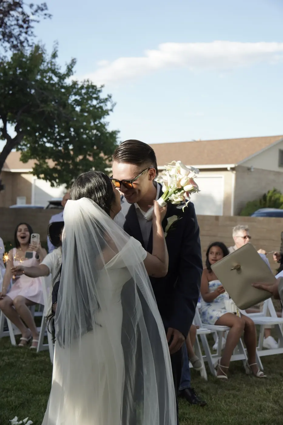 Los novios se besan al final de la ceremonia mientras los invitados celebran con bengalas
