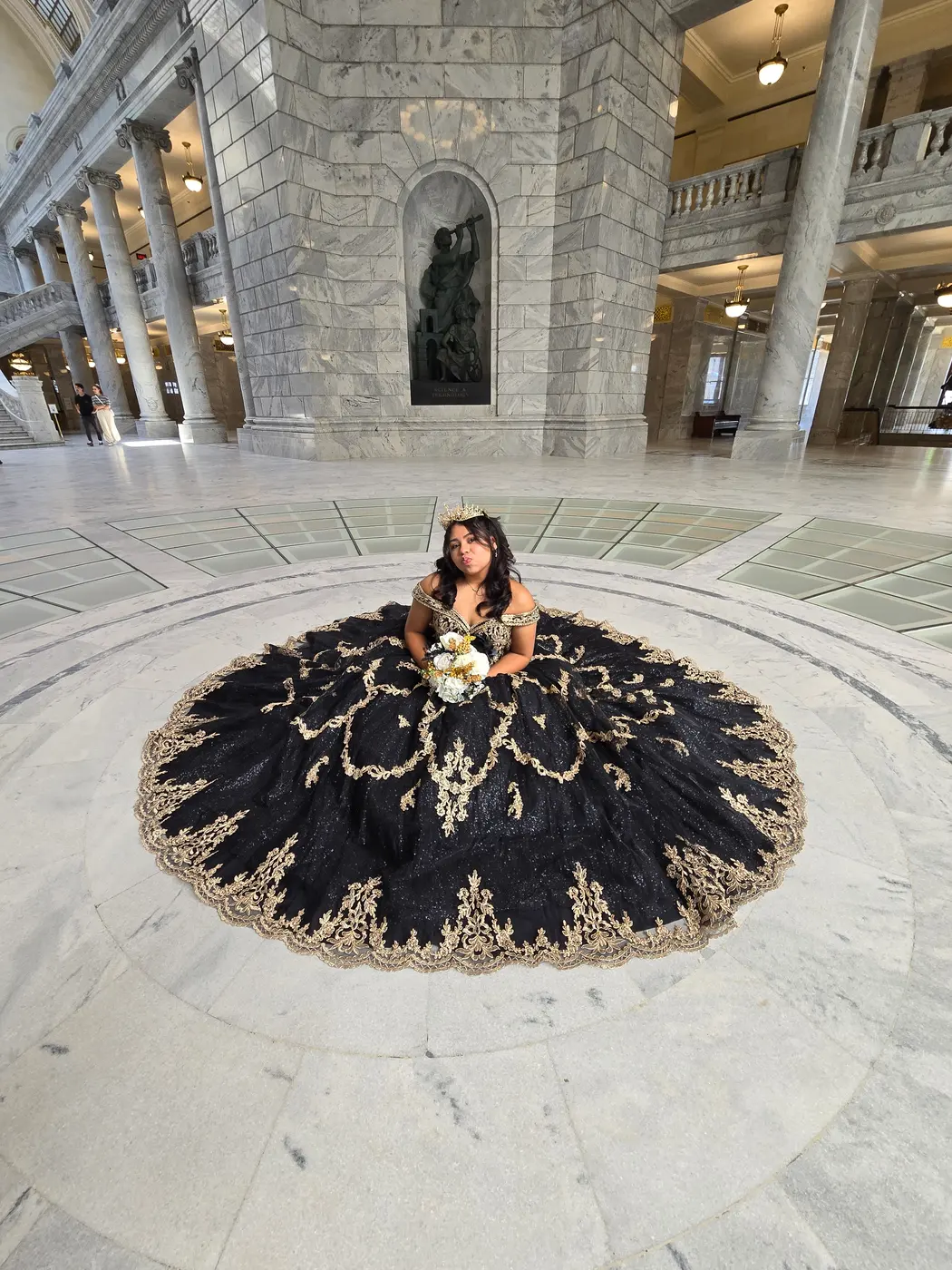 Quinceañera sentada con su vestido extendido en la rotonda del Capitolio de Utah
