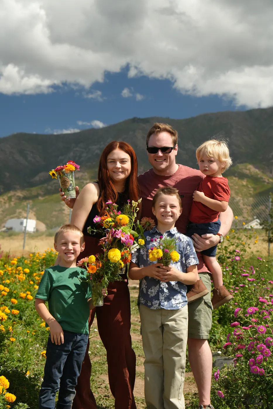 Familia con tres niños y ramos de flores frente a las montañas