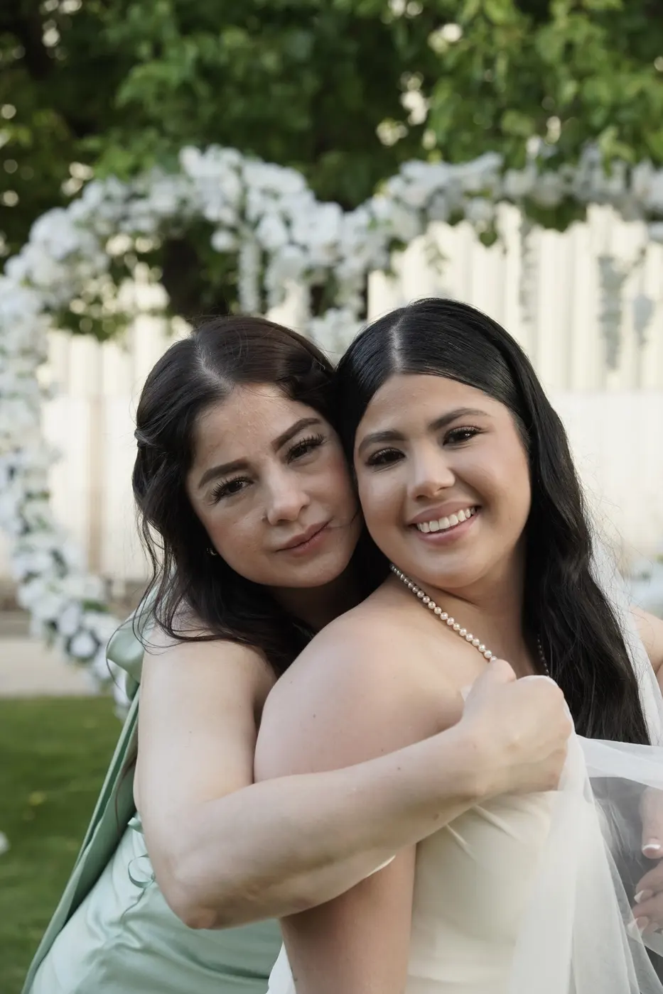 La novia y su mamá abrazadas mejilla con mejilla